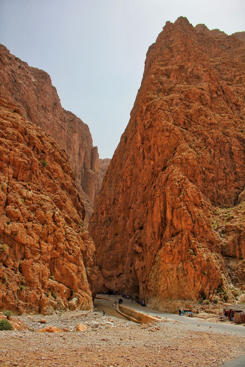 A breathtaking view of Todgha Gorges in Morocco, showcasing towering limestone cliffs with a narrow river flowing through the dramatic canyon